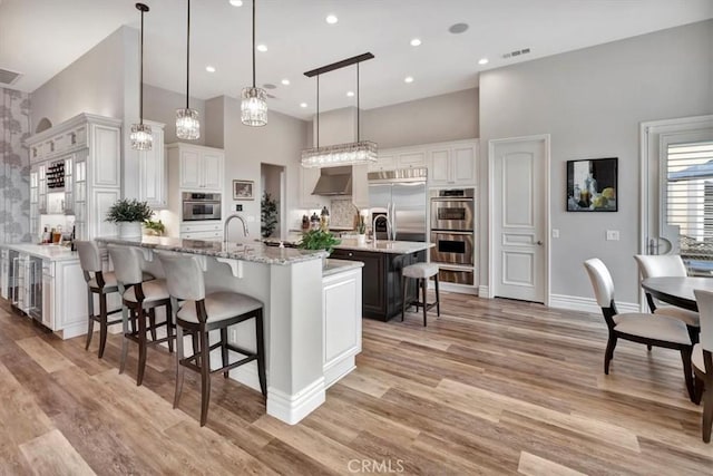 kitchen featuring visible vents, appliances with stainless steel finishes, a high ceiling, and a breakfast bar area