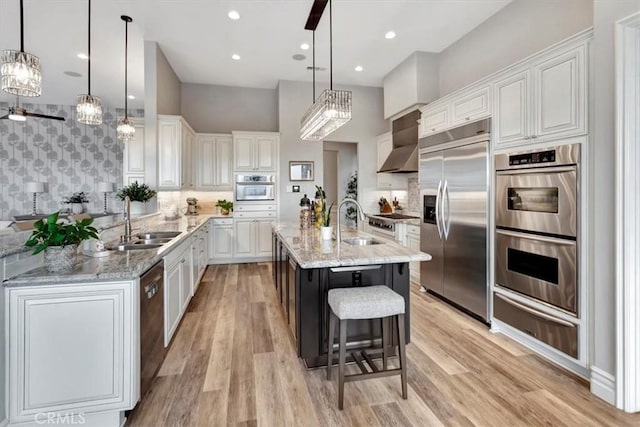 kitchen with a sink, appliances with stainless steel finishes, wall chimney exhaust hood, and a warming drawer