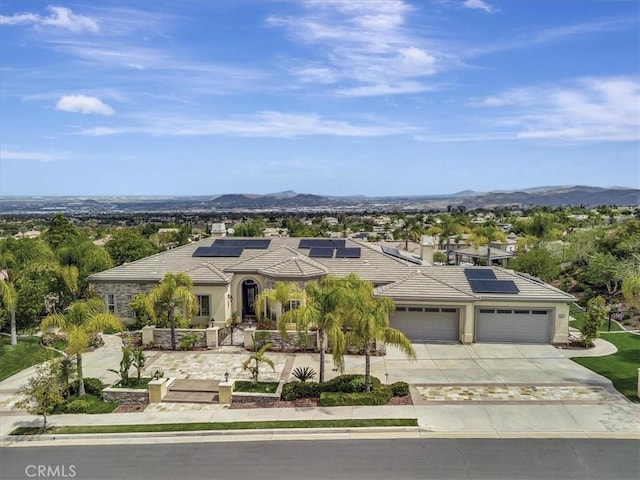 view of front of property with an attached garage, stucco siding, roof mounted solar panels, concrete driveway, and a tiled roof