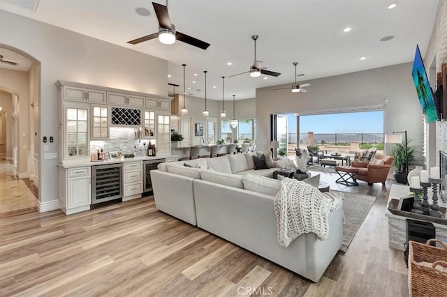 living room featuring beverage cooler, a ceiling fan, and arched walkways
