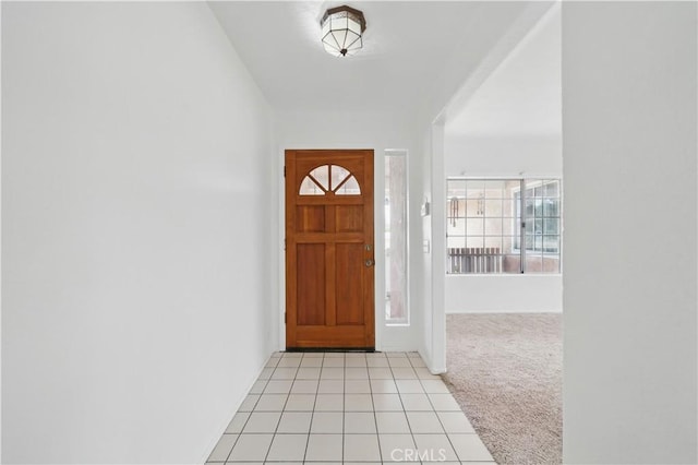 entryway with light colored carpet and light tile patterned floors