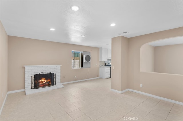 unfurnished living room with a brick fireplace, recessed lighting, visible vents, and baseboards