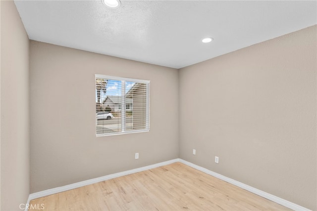 unfurnished room with recessed lighting, wood finished floors, and baseboards