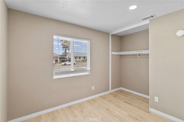 unfurnished bedroom featuring recessed lighting, a closet, visible vents, baseboards, and wood finished floors