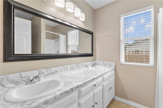 full bathroom with curtained shower, double vanity, a sink, and baseboards