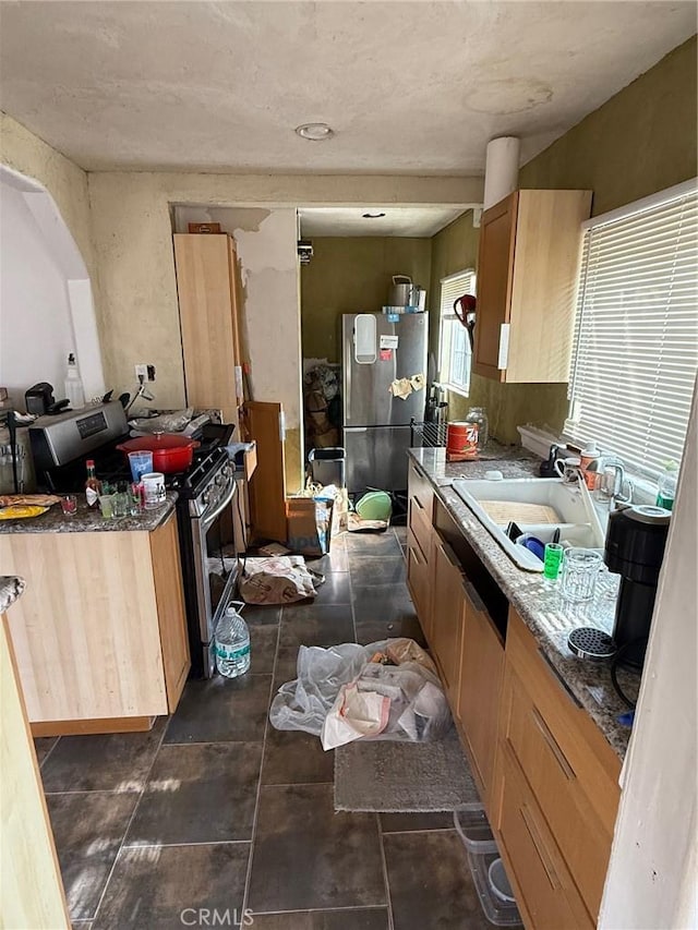 kitchen featuring stainless steel appliances, dark tile patterned floors, and a sink