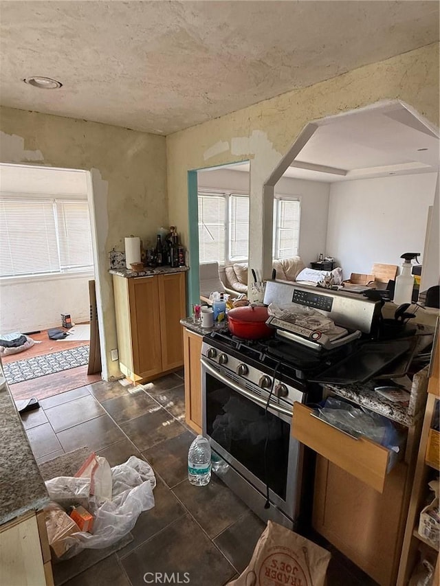 kitchen with dark tile patterned floors and stainless steel gas stove