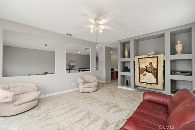 carpeted living room with built in shelves, visible vents, ceiling fan, and baseboards