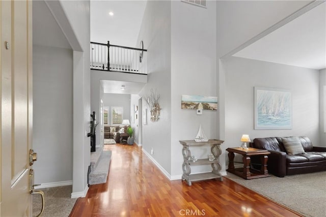 entrance foyer featuring a high ceiling, visible vents, wood finished floors, and baseboards