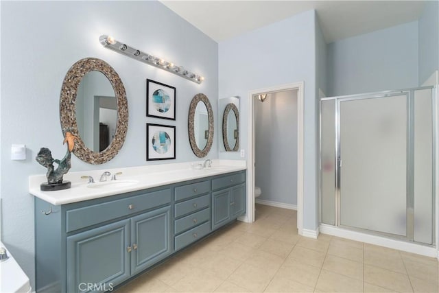 bathroom featuring double vanity, toilet, a stall shower, and a sink