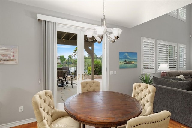 dining area with light wood-type flooring, an inviting chandelier, and baseboards