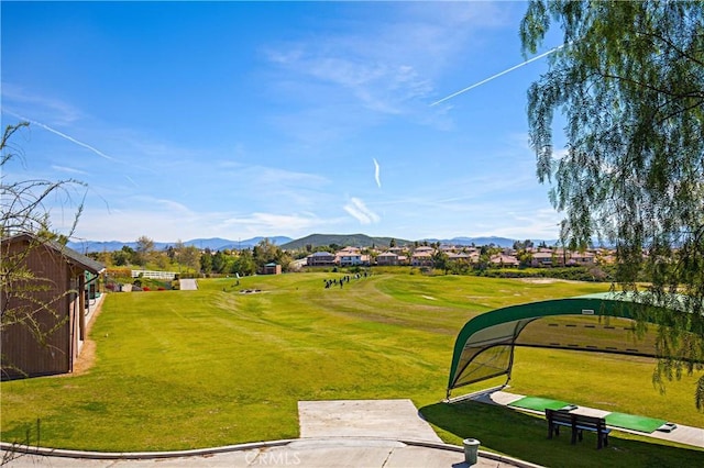 view of property's community with a yard, a mountain view, and view of golf course