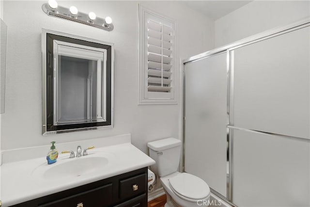 full bath featuring a shower with shower door, toilet, and vanity