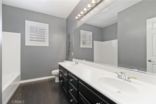 full bathroom with a bathing tub, toilet, baseboards, and a sink
