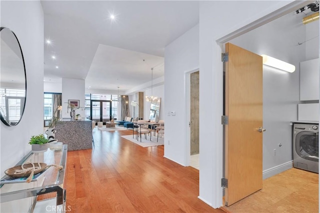 hall with light wood finished floors, recessed lighting, a chandelier, and washer / dryer