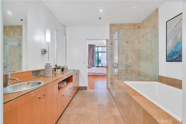 ensuite bathroom featuring a sink, a bath, ensuite bath, a stall shower, and double vanity
