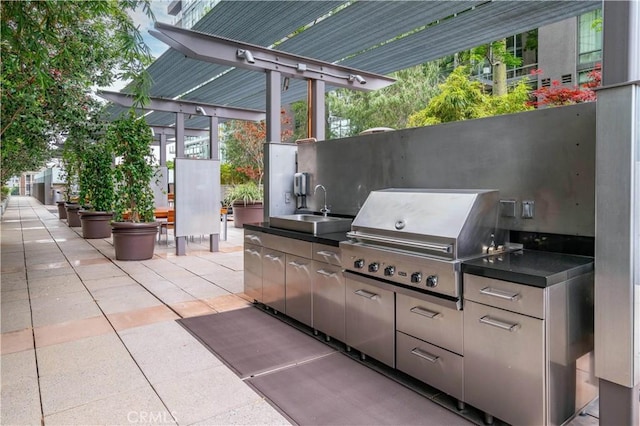 view of patio with exterior kitchen, area for grilling, and a sink