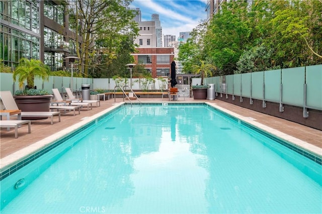 pool featuring a view of city, a patio, and a fenced backyard