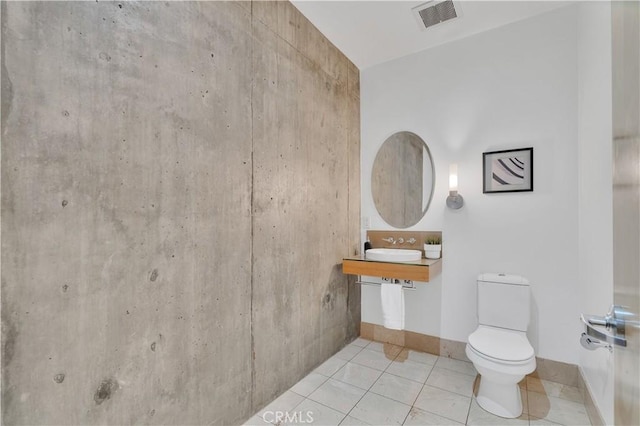 bathroom with a sink, toilet, visible vents, baseboards, and tile patterned flooring