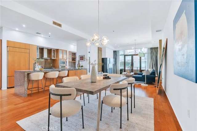 dining room with visible vents, a notable chandelier, and light wood-style flooring