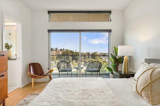 bedroom featuring wood finished floors, ensuite bath, multiple windows, and access to exterior