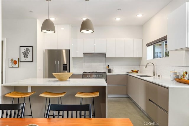 kitchen with appliances with stainless steel finishes, a breakfast bar, modern cabinets, and a sink