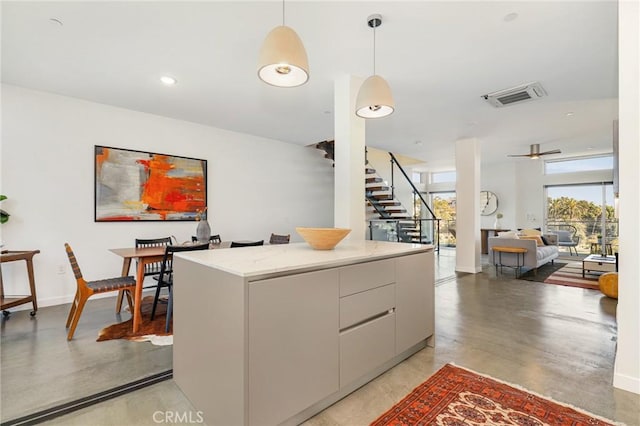 kitchen featuring modern cabinets, visible vents, decorative light fixtures, a kitchen island, and light countertops
