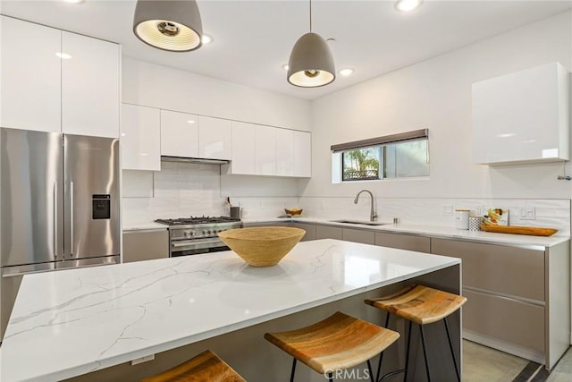 kitchen with white cabinetry, a sink, stainless steel appliances, a kitchen bar, and modern cabinets
