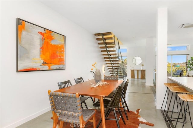 dining area featuring baseboards, visible vents, and finished concrete floors