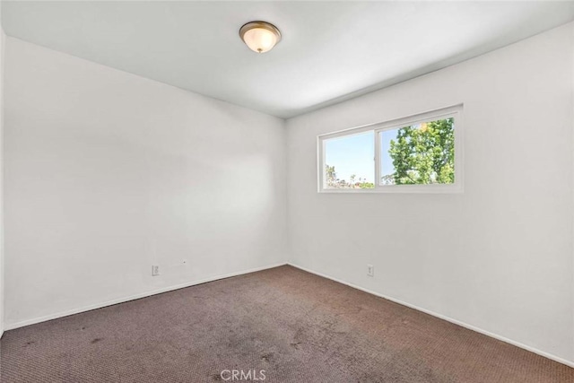 carpeted empty room featuring baseboards