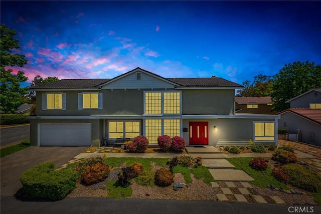 traditional home with stucco siding, an attached garage, and aphalt driveway