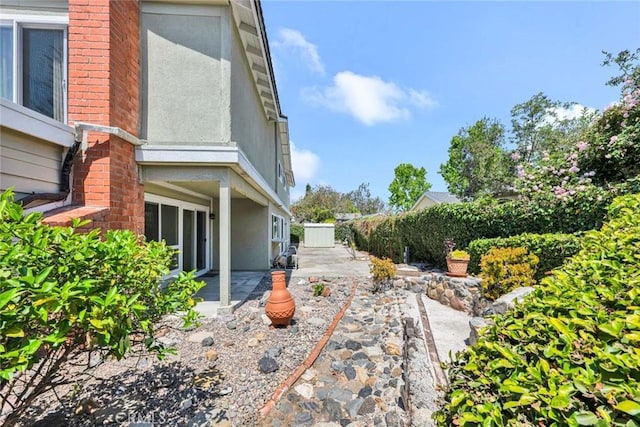 view of home's exterior featuring brick siding, stucco siding, and a patio area