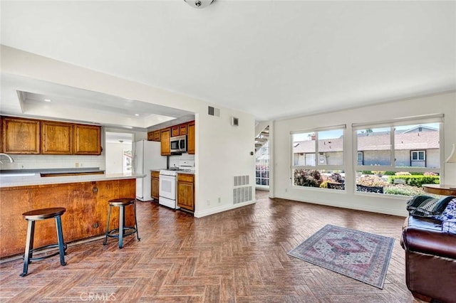 living room with stairway, visible vents, a tray ceiling, and baseboards