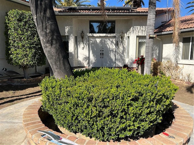 exterior space featuring stucco siding, solar panels, and a tile roof