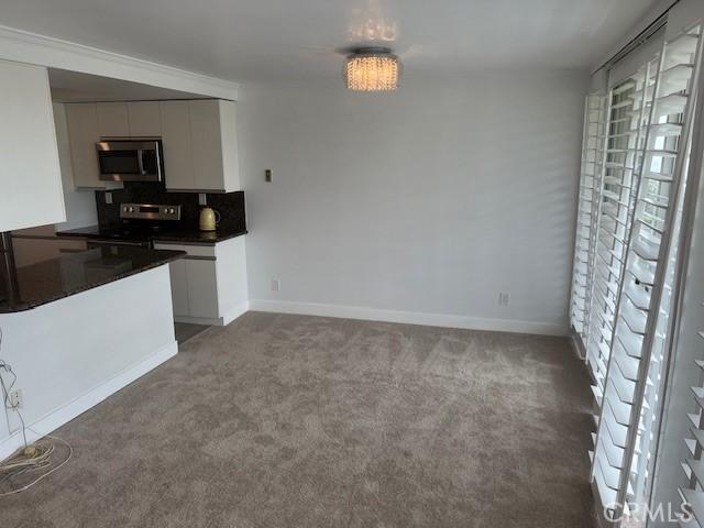 32679 Seagate Dr Unit 308-H, Rancho Palos Verdes, CA 90275 - kitchen with carpet floors, dark countertops, baseboards, white cabinets, and stainless steel appliances