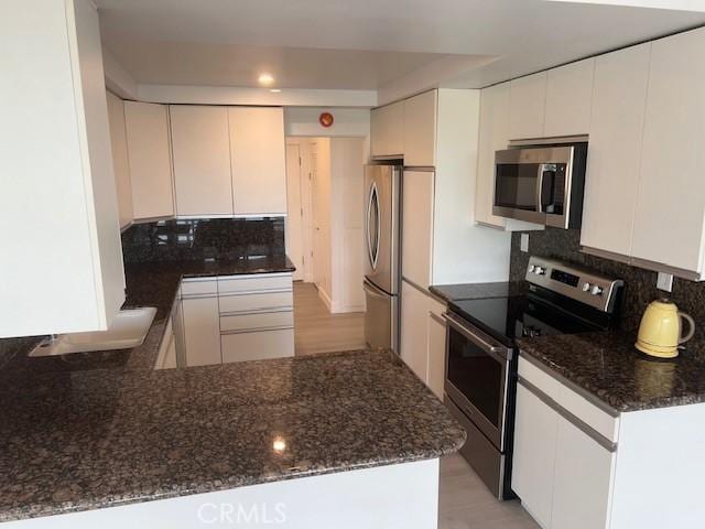 32679 Seagate Dr Unit 308-H, Rancho Palos Verdes, CA 90275 - kitchen featuring decorative backsplash, dark stone counters, and stainless steel appliances