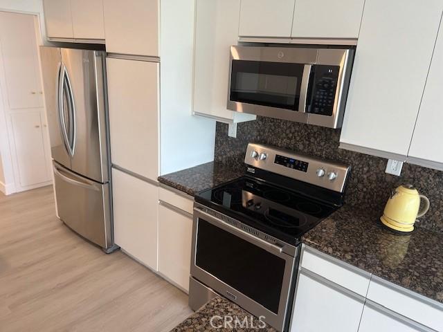 32679 Seagate Dr Unit 308-H, Rancho Palos Verdes, CA 90275 - kitchen with decorative backsplash, light wood-style flooring, white cabinets, and stainless steel appliances