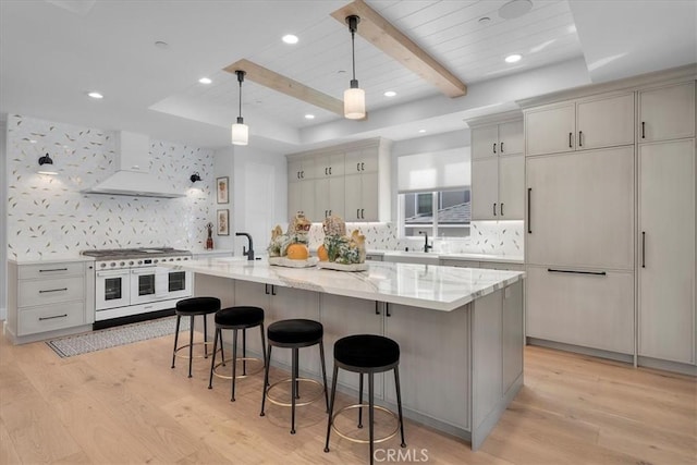 507 N Maria Ave Unit A, Redondo Beach, CA 90277 - kitchen with double oven range, extractor fan, a breakfast bar area, light wood-style flooring, and decorative backsplash