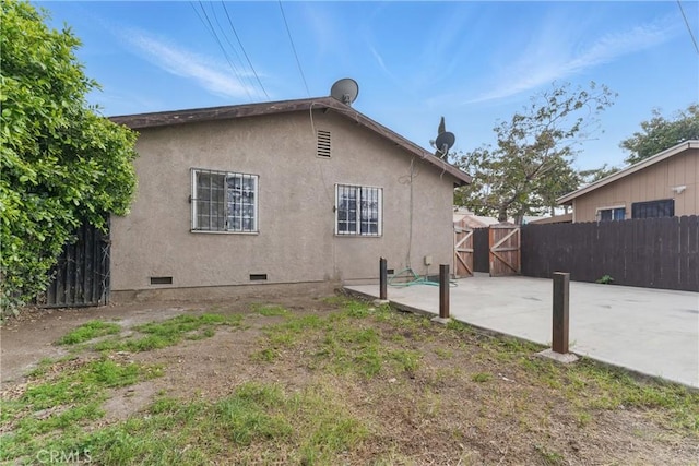 907 E 109th Pl, Los Angeles, CA 90059 - rear view of house featuring fence, a gate, stucco siding, and crawl space