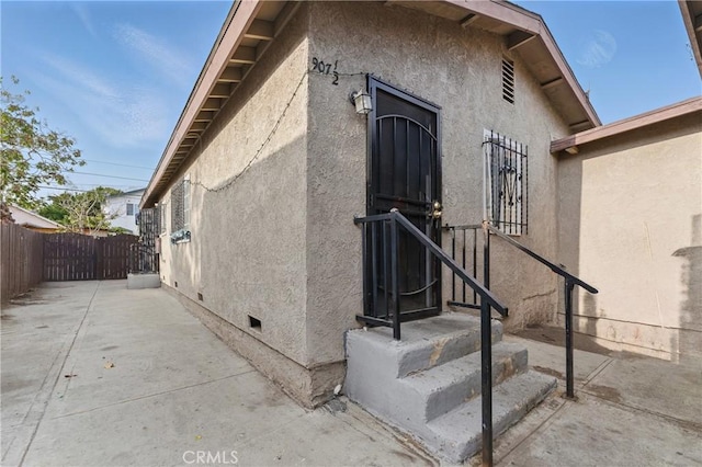 907 E 109th Pl, Los Angeles, CA 90059 - doorway to property with crawl space, fence, a patio, and stucco siding
