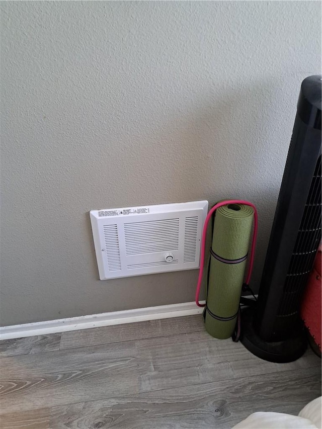 interior details featuring baseboards, heating unit, and wood finished floors