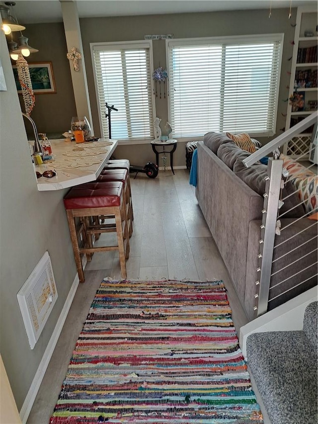 living room featuring baseboards, visible vents, a wealth of natural light, and light wood-type flooring