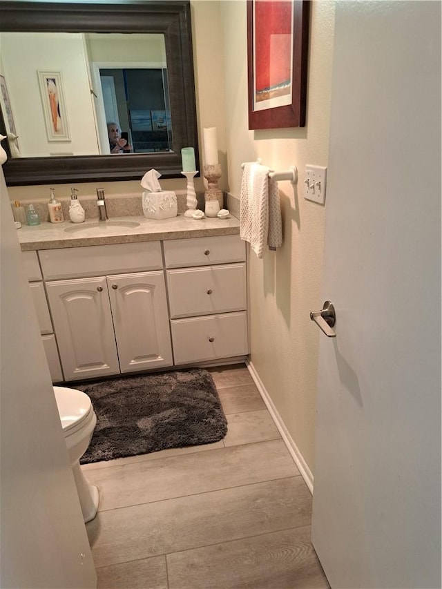bathroom with vanity, baseboards, toilet, and wood finished floors