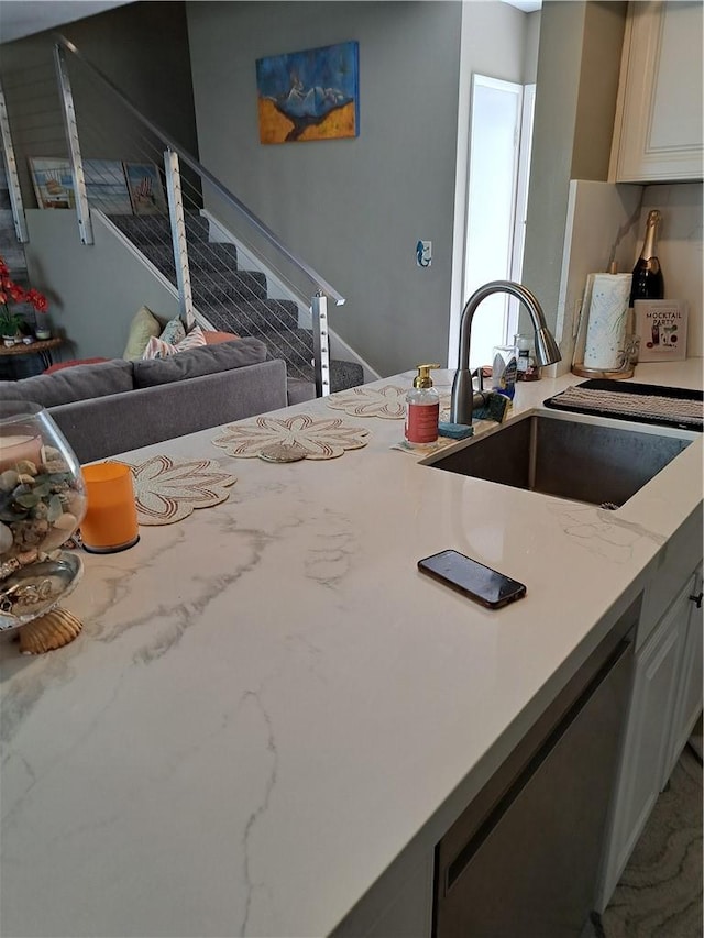 kitchen with a sink, light stone countertops, open floor plan, and dishwasher