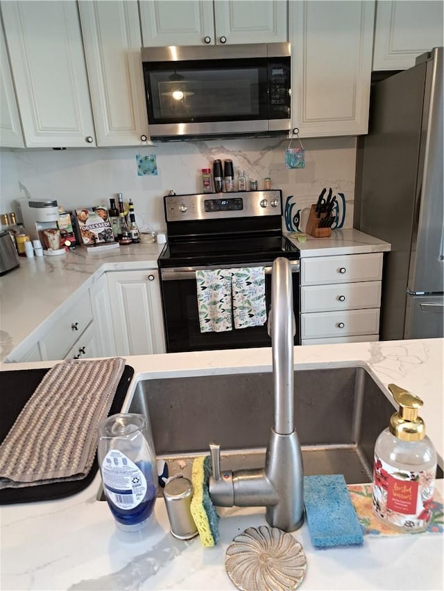 711 Pacific Coast Hwy Unit 418, Huntington Beach, CA 92648 - kitchen with appliances with stainless steel finishes, white cabinets, and decorative backsplash