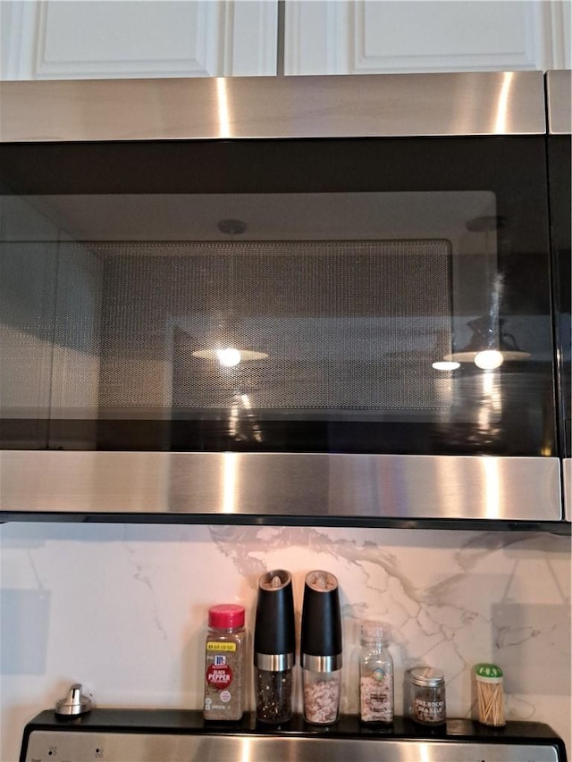 interior details with white cabinets, wall oven, and decorative backsplash