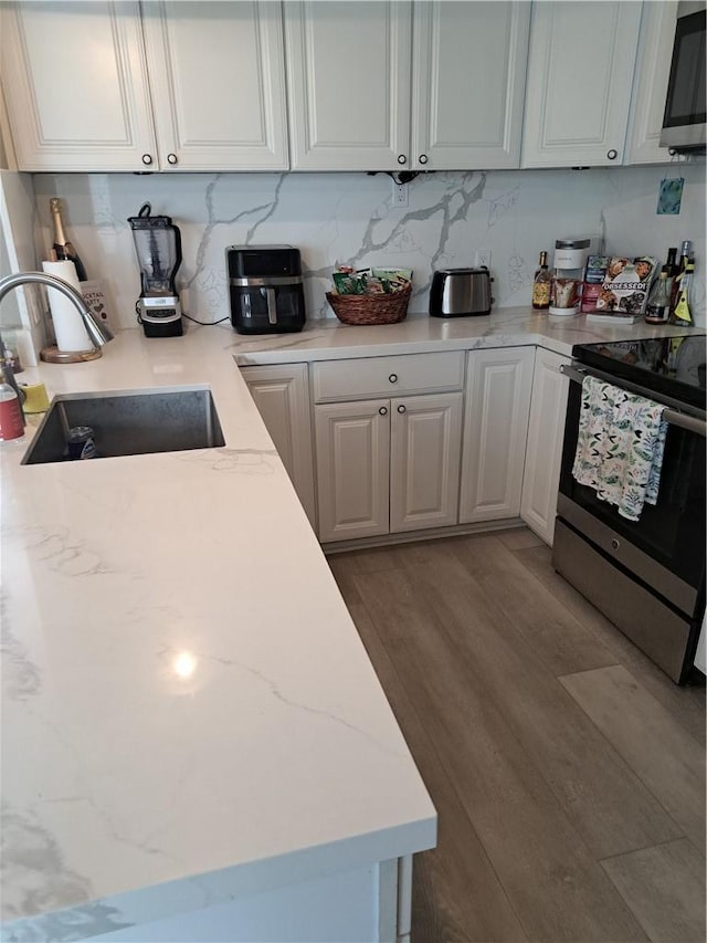 711 Pacific Coast Hwy Unit 418, Huntington Beach, CA 92648 - kitchen featuring appliances with stainless steel finishes, wood finished floors, white cabinets, tasteful backsplash, and light stone counters