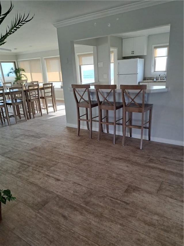 711 Pacific Coast Hwy Unit 418, Huntington Beach, CA 92648 - kitchen featuring freestanding refrigerator, ornamental molding, a breakfast bar area, and a peninsula