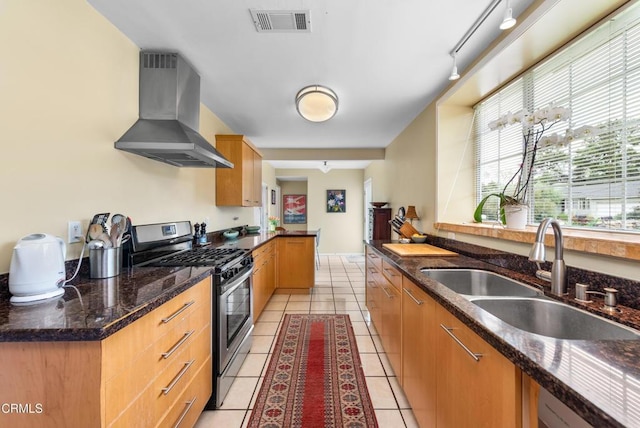 kitchen with visible vents, stainless steel gas stove, a sink, light tile patterned flooring, and wall chimney exhaust hood