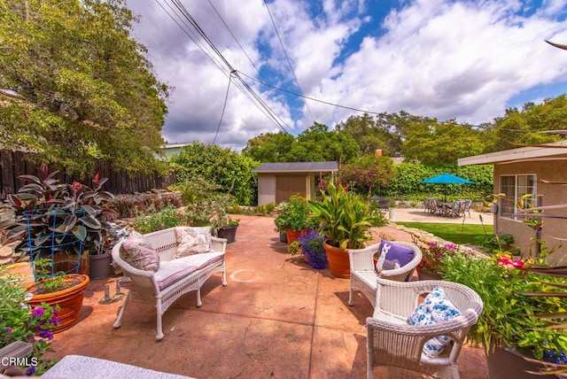 view of patio / terrace featuring fence, outdoor dining area, a shed, an outdoor living space, and an outbuilding